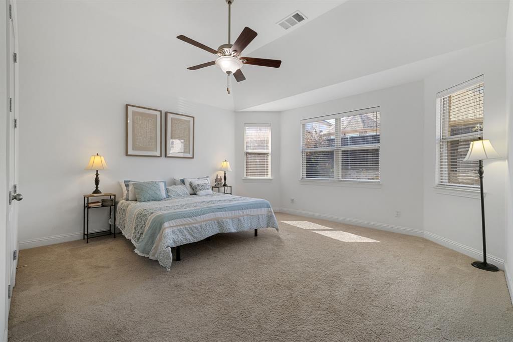 5504 Ripasso Street McKinney, TX 75070 - Photo 25 of 40 a spacious bedroom with a bed and a chandelier