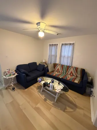 a living room with couches and a ceiling fan