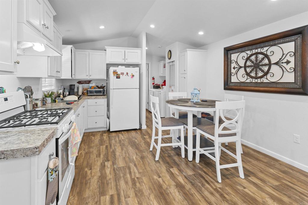 3221 Bancroft Drive, Unit 25 Spring Valley, CA 91977 - Photo 3 of 17 a kitchen with stainless steel appliances granite countertop a stove top oven a refrigerator a dining table and chairs with wooden floor