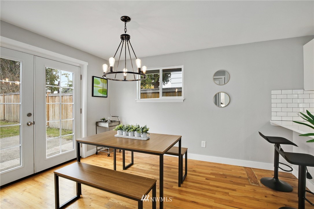 10014 40th Avenue Southwest Seattle, WA 98146 - Photo 15 of 36 a dining room with wooden floor a chandelier a wooden table and chairs