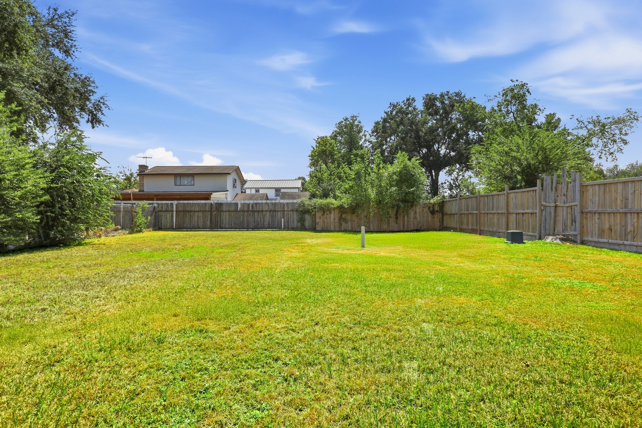 1507 Willow Rock Road Houston, TX 77088 - Photo 7 of 27 Expansive backyard lawn with privacy fencing and mature trees along the fence line for a green backdrop.