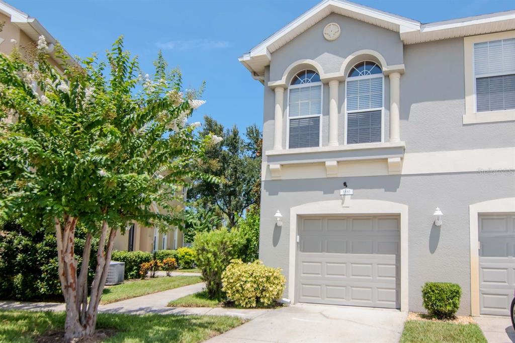 a view of a white house with a small yard and plants