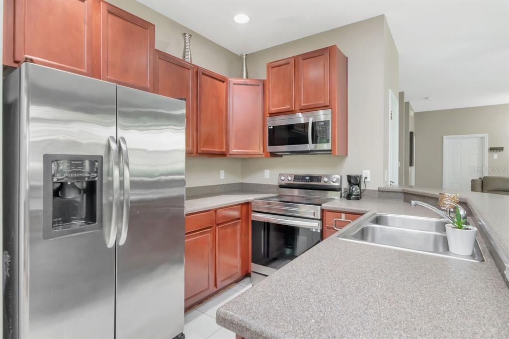 8880 Moonlit Meadows Loop Riverview, FL 33578 - Photo 18 of 43 a kitchen with stainless steel appliances granite countertop a refrigerator a stove and a sink with wooden floor