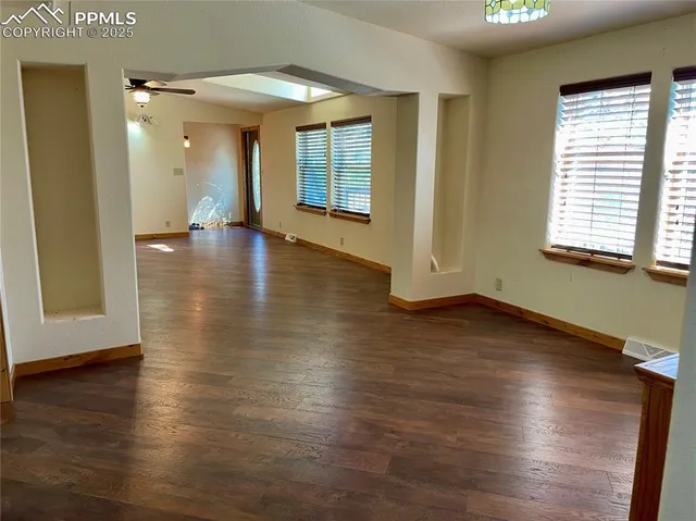an empty room with wooden floor and windows