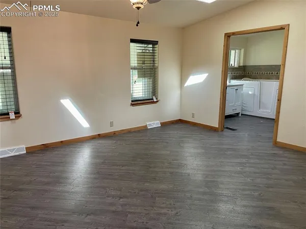 an empty room with wooden floor and windows