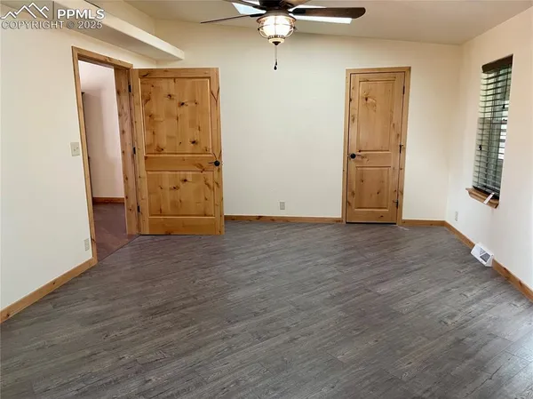 an empty room with wooden floor closet and windows