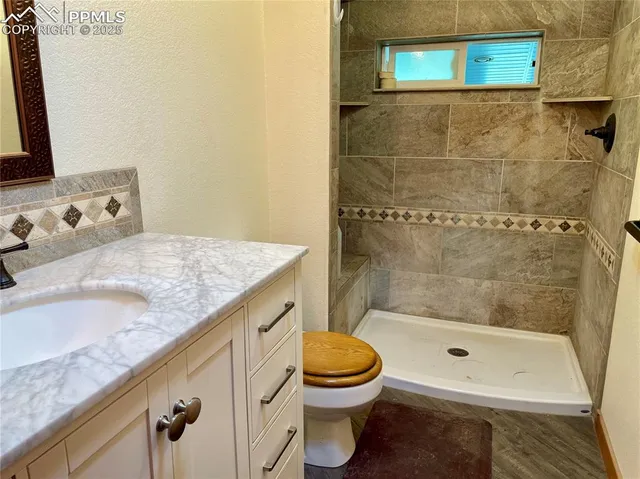 a bathroom with a granite countertop bathtub sink vanity mirror and toilet