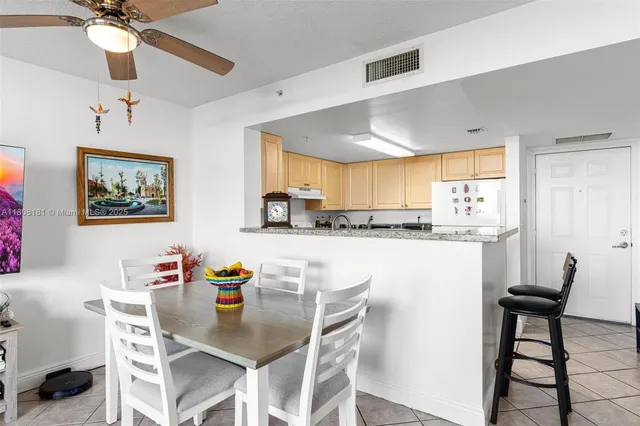 a kitchen with stainless steel appliances granite countertop a dining table chairs refrigerator and sink