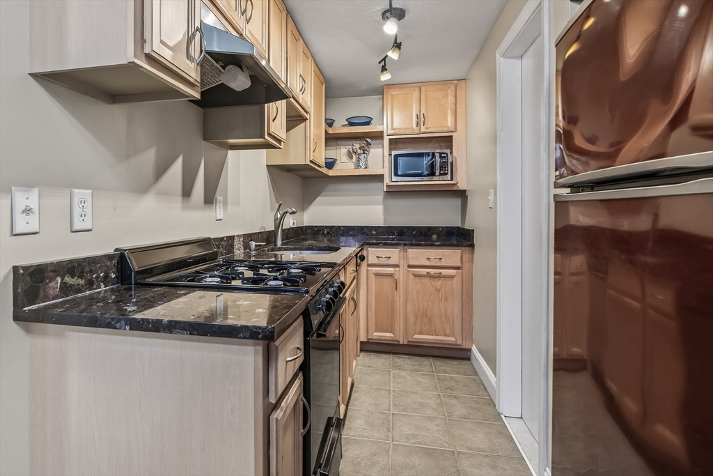 64 Commonwealth Avenue, Unit G1 Boston, MA 02116 - Photo 10 of 12 a kitchen with stainless steel appliances granite countertop a stove and a sink