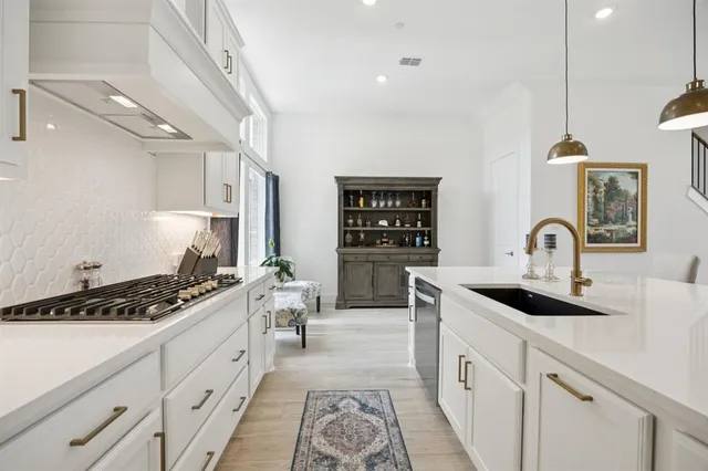 a kitchen with stainless steel appliances kitchen island granite countertop a stove top oven a sink a dining table and chairs with wooden floor