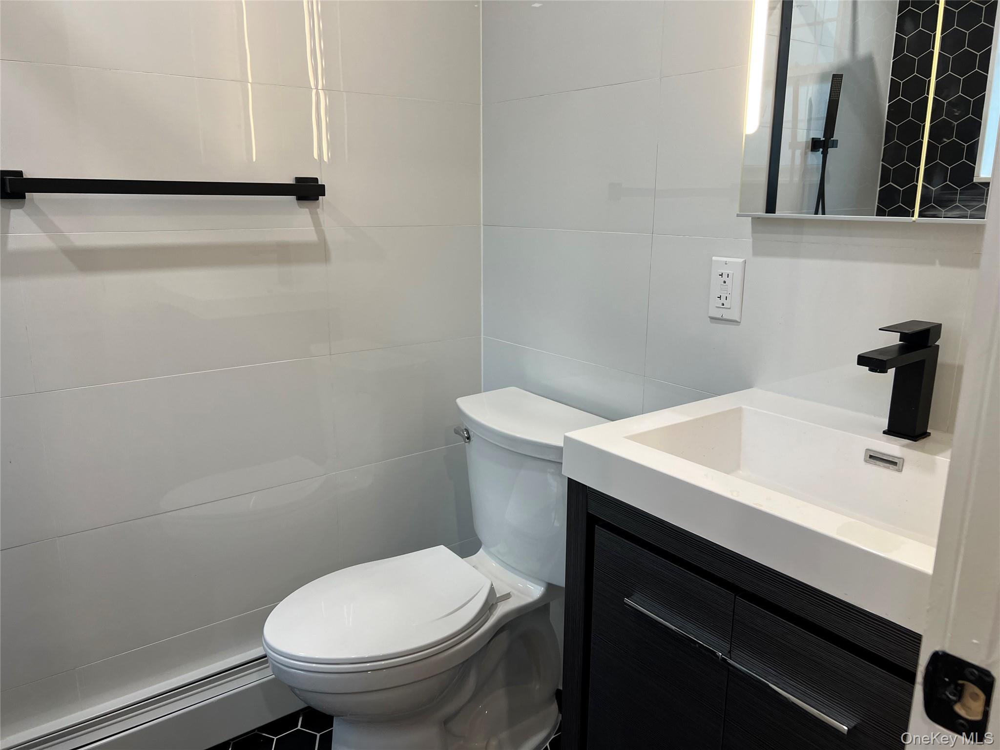 89-21 69th Road, Unit 2R Queens, NY 11375 - Photo 11 of 16 a bathroom with a sink a toilet and a mirror