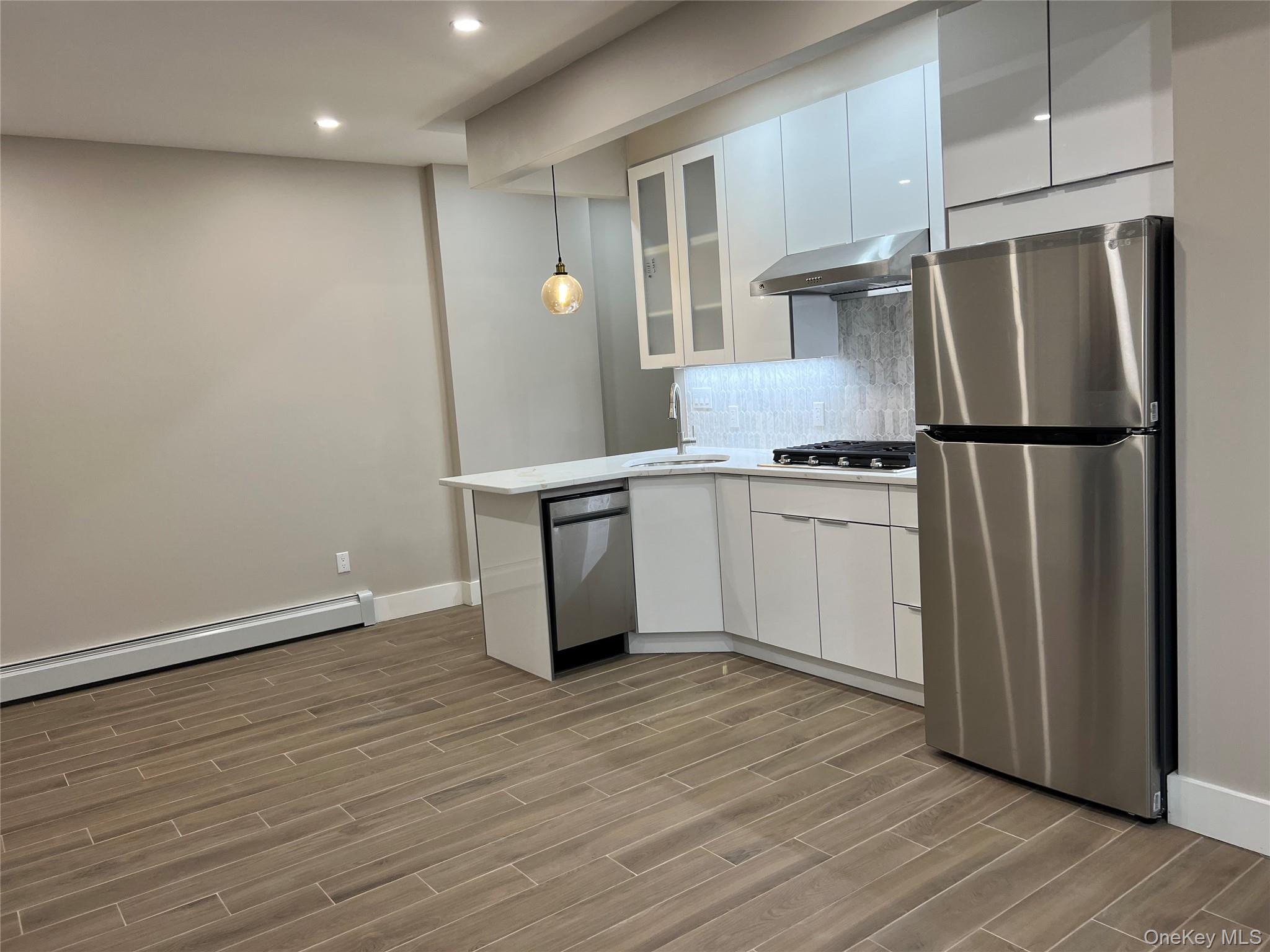 89-21 69th Road, Unit 2R Queens, NY 11375 - Photo 2 of 16 a kitchen with stainless steel appliances a refrigerator and wooden floor