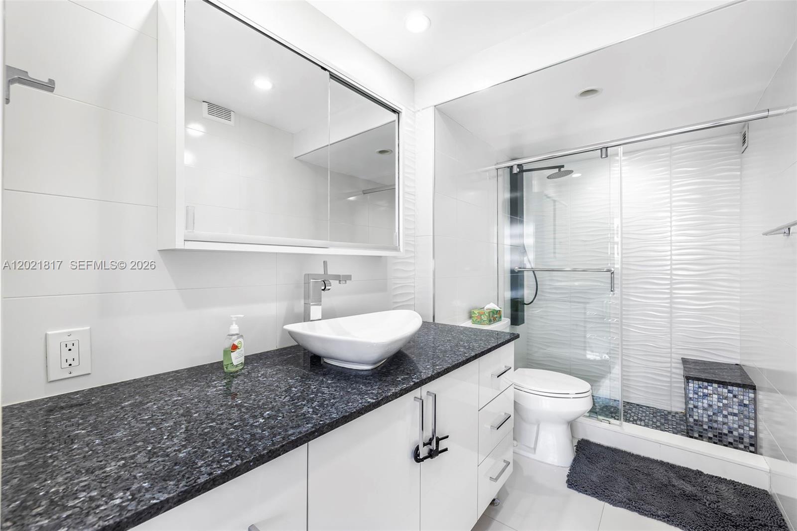 9511 Collins Avenue, Unit 1202 Surfside, FL 33154 - Photo 14 of 16 a bathroom with a granite countertop sink and a mirror