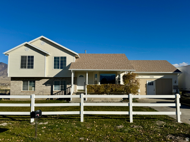 3908 Campbell Road Erda, UT 84074 - Photo 1 of 1 View of front of home with a porch, a fenced front yard, concrete driveway, and a shingled roof