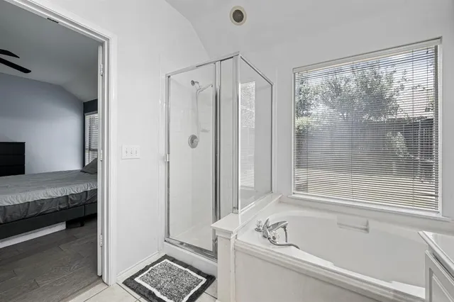 a bathroom with a tub a mirror and a shower