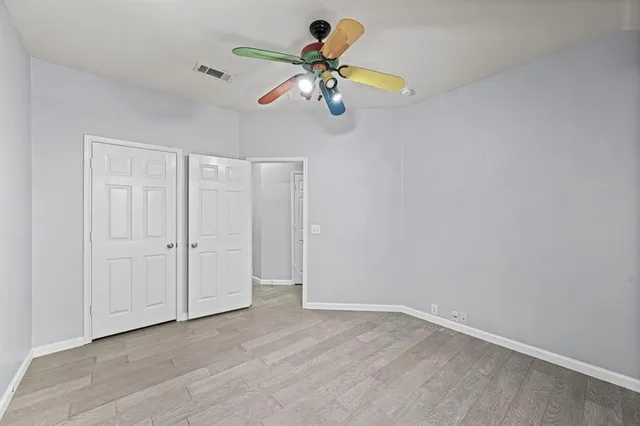 a view of an empty room with window and chandelier fan