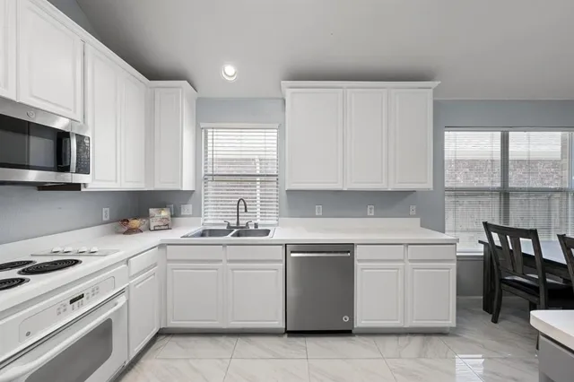a kitchen with cabinets appliances a sink and a window