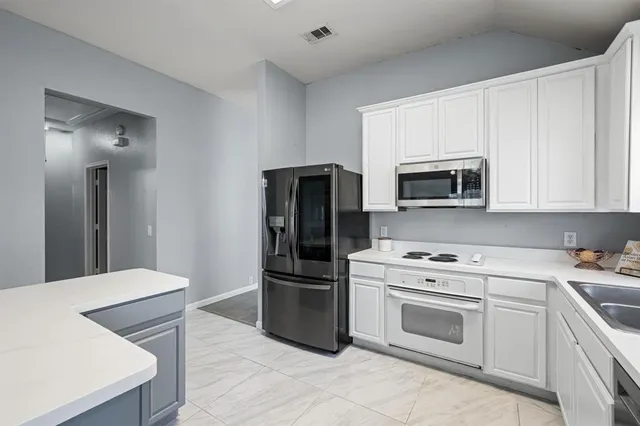 a kitchen with white cabinets and stainless steel appliances