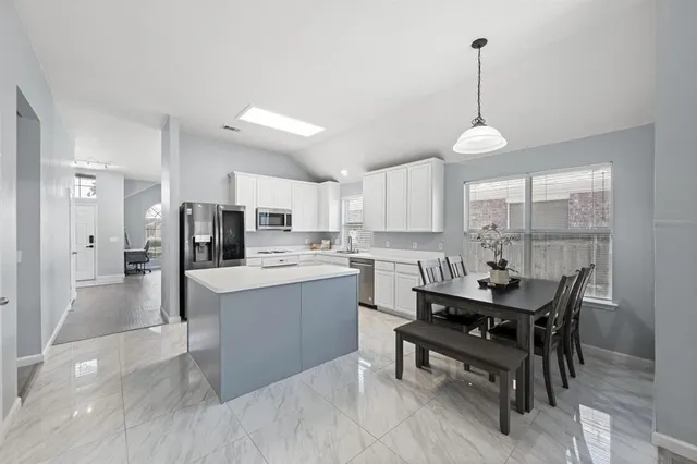 a kitchen with a table chairs refrigerator and cabinets