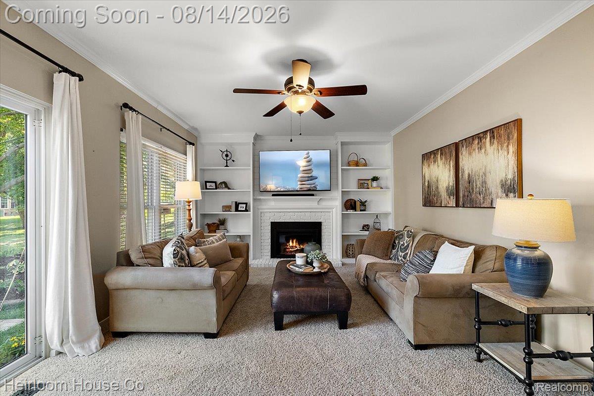45697 Bryn Mawr Road Canton, MI 48187 - Photo 60 of 75 Spacious living area featuring a fireplace with a white mantel, built-in shelving, a ceiling fan, and carpet flooring