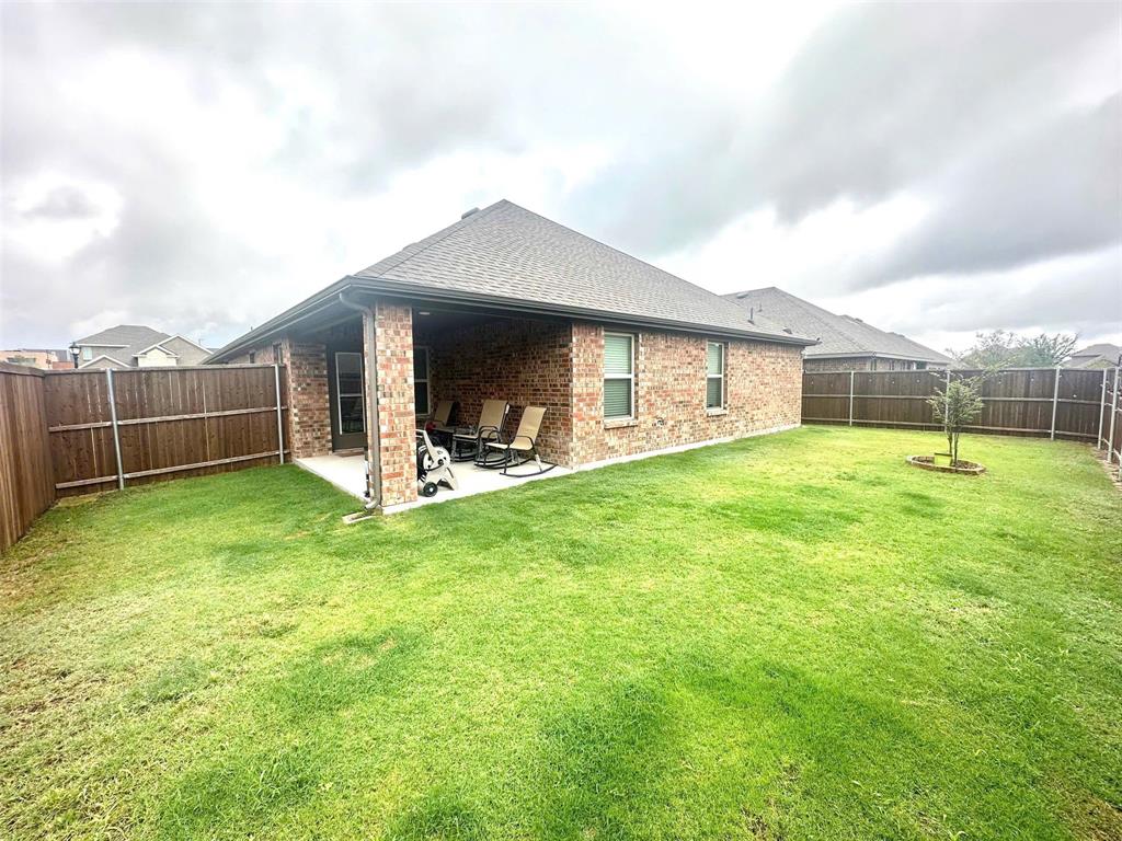324 Revolution Road Fate, TX 75189 - Photo 15 of 15 Expansive backyard featuring a covered patio, brick exterior, shingle roof, and a privacy fence