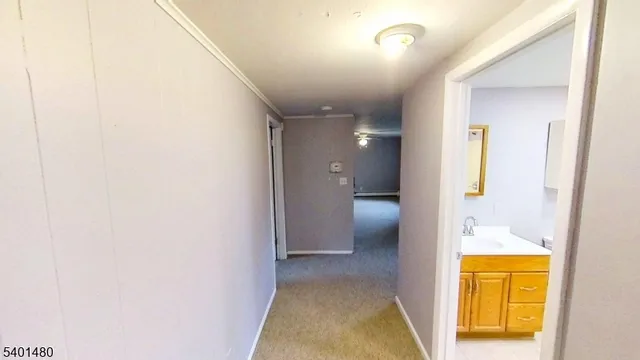 a view of a hallway with wooden floor and a bathroom