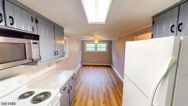 a view of a kitchen with a fridge and wooden floor
