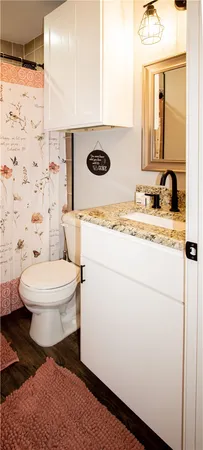 a bathroom with a granite countertop toilet sink and mirror