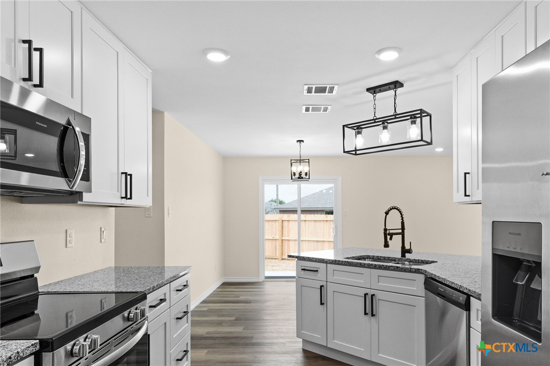 5222 Rose Gdn Loop Killeen, TX 76542 - Photo 6 of 25 a kitchen with cabinets wooden floor and stainless steel appliances