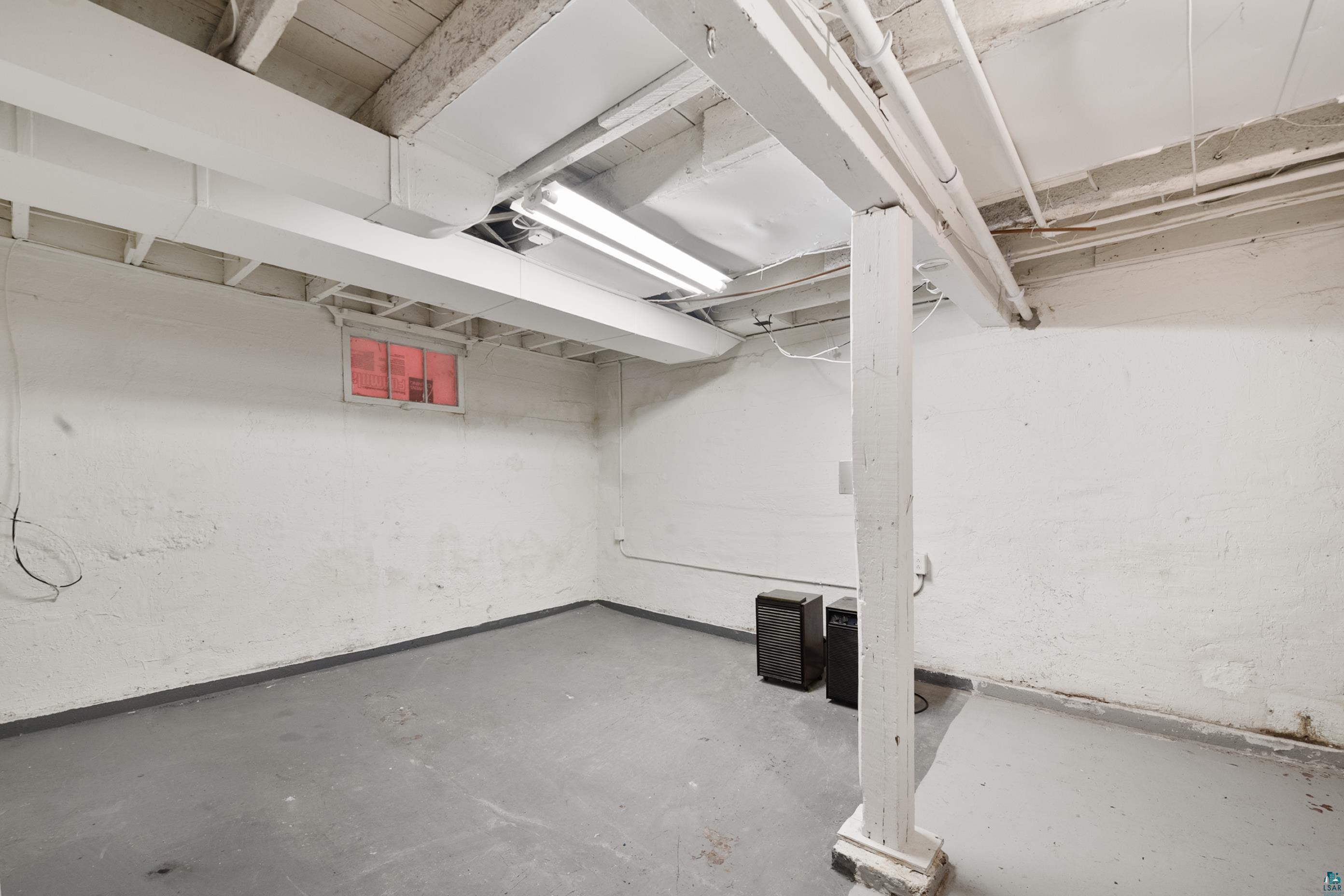 3067 Restormel Street Duluth, MN 55806 - Photo 18 of 25 Unfinished basement space featuring exposed ceiling joists and ductwork, white painted cinder block walls, a small window opening, and concrete flooring