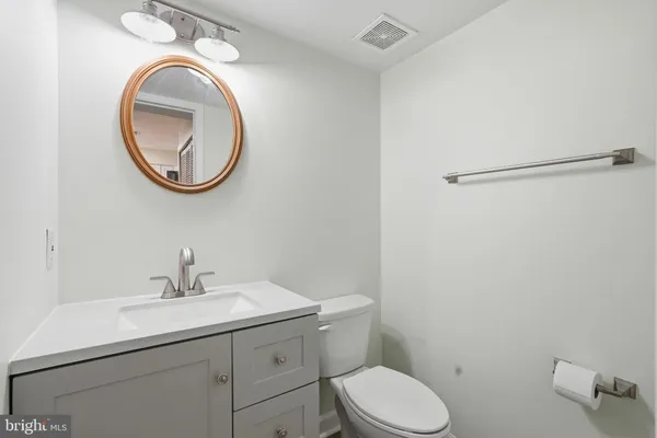 a bathroom with a toilet sink vanity and mirror