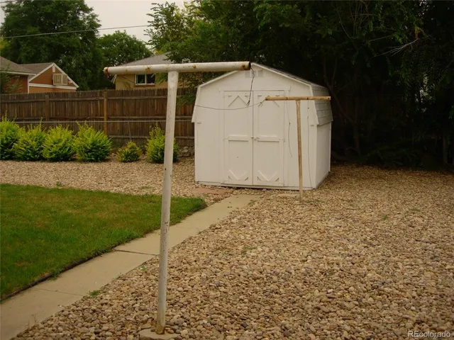 a view of a barn house next to a yard with wooden fence