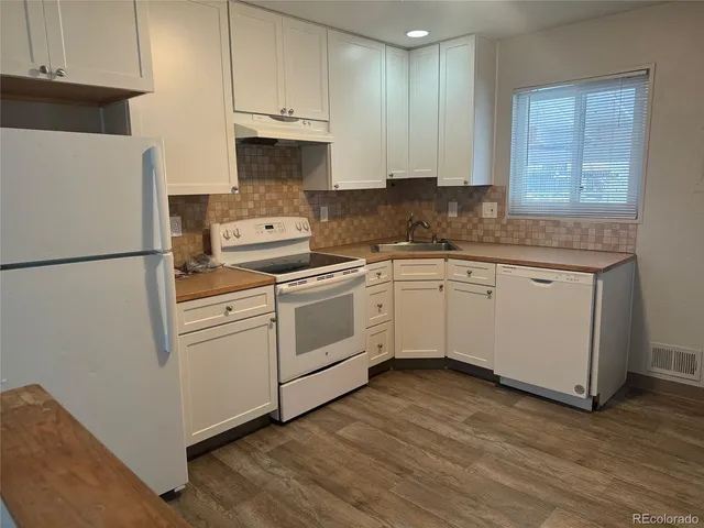 a kitchen with cabinets appliances and wooden floor