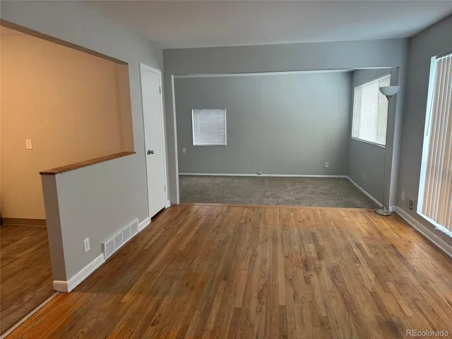an empty room with wooden floor and windows