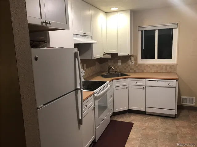 a kitchen with white cabinets and white appliances