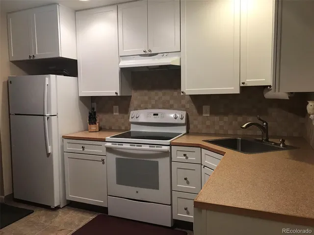 a kitchen with stainless steel appliances granite countertop a stove a refrigerator and a white cabinets