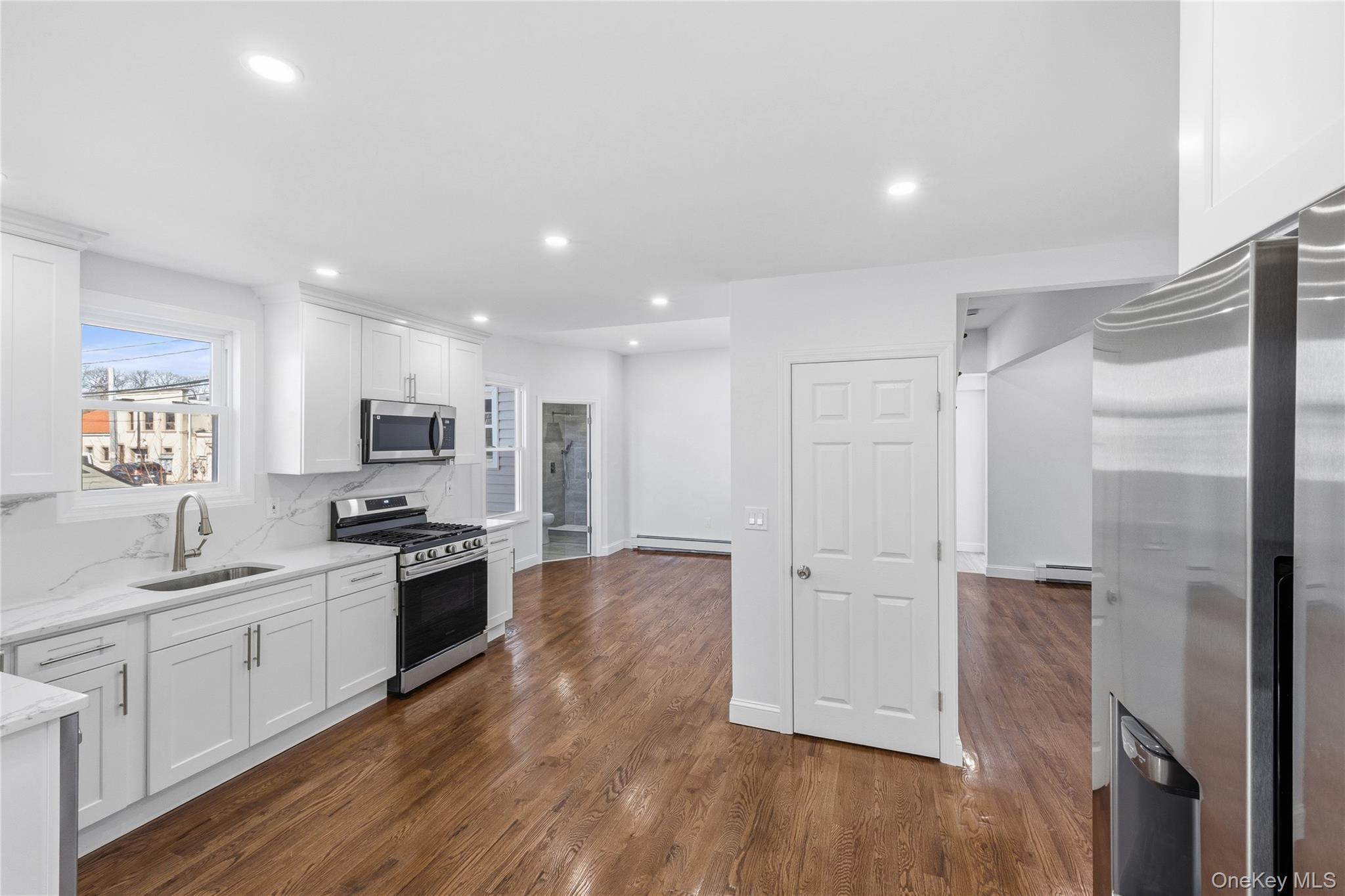 22 Colonial Avenue Freeport, NY 11520 - Photo 19 of 41 a kitchen with stainless steel appliances granite countertop a refrigerator a sink a stove and white cabinets with wooden floor
