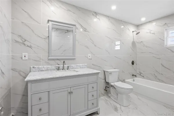 a bathroom with a granite countertop sink a toilet and a bathtub