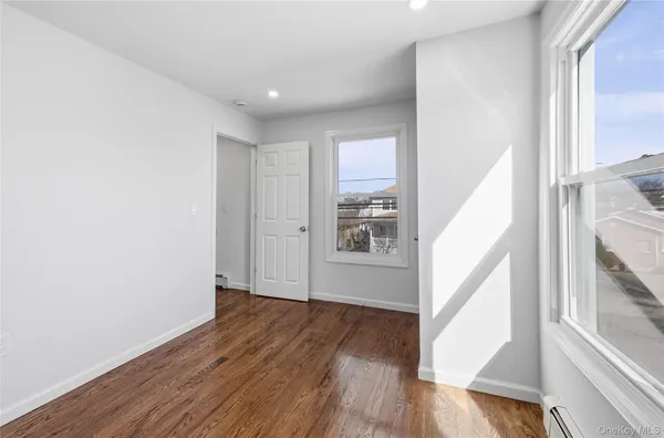 a view of hallway with window and wooden floor