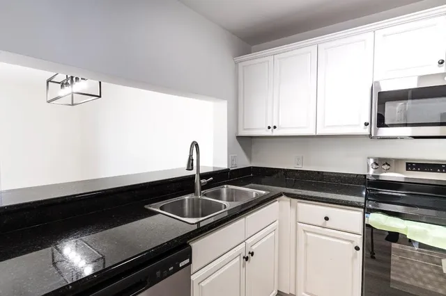 a kitchen with granite countertop white cabinets and black appliances