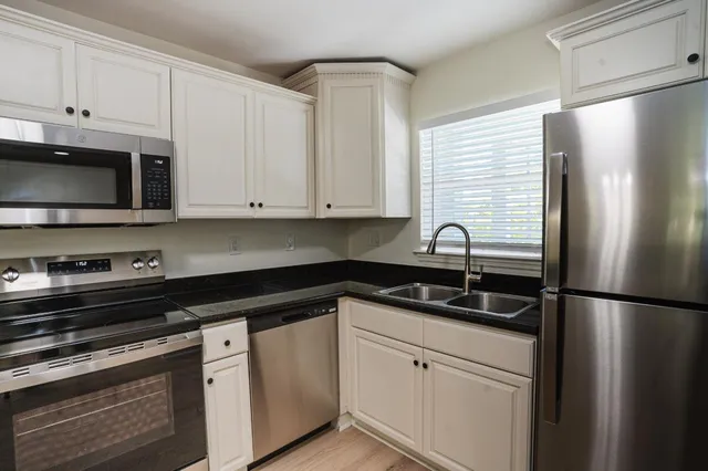 a white kitchen with granite countertop white cabinets and stainless steel appliances
