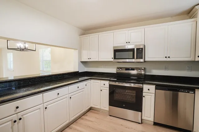 a kitchen with granite countertop white cabinets and black appliances