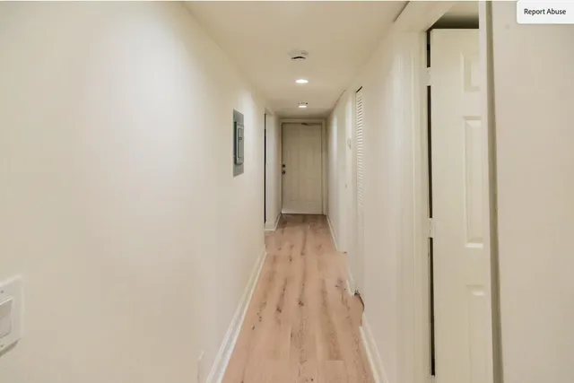 a view of a hallway with wooden floor and a bathroom