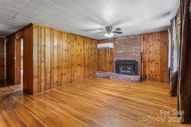 a view of an empty room with wooden floor fireplace and a window