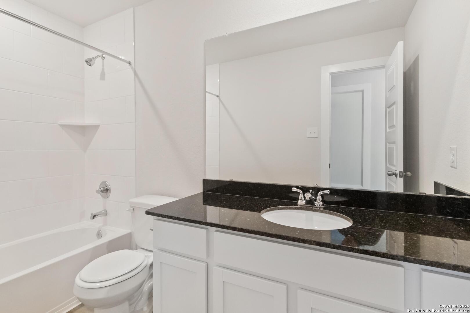 10303 Apple Pie Road San Antonio, TX 78224 - Photo 28 of 31 a bathroom with a granite countertop sink a toilet a mirror and shower