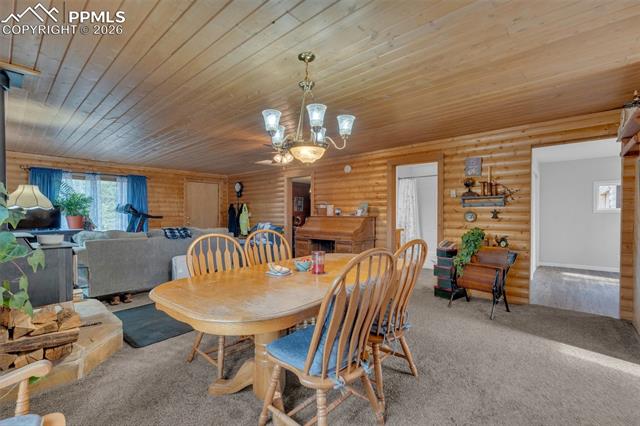 847 Timber Ridge Road Divide, CO 80814 - Photo 11 of 41 Expansive room with wood-paneled walls and ceiling, featuring a central dining area with a chandelier