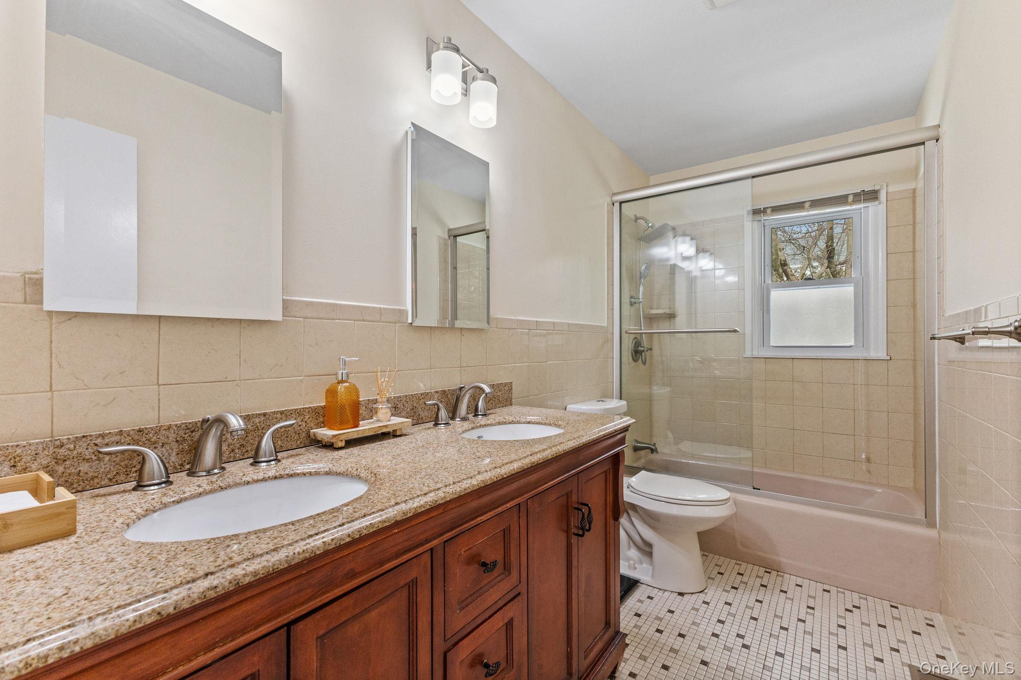15 Meadow Place Rye, NY 10580 - Photo 20 of 39 One of three main floor full baths, with double-sink granite vanity top, glass shower door, tiled walls and floor.