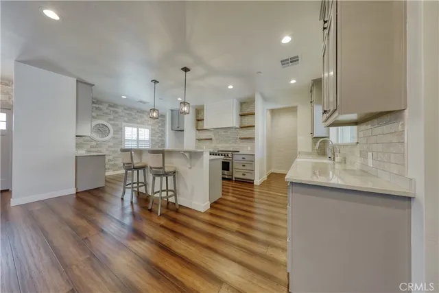a kitchen with stainless steel appliances wooden floor and a stove
