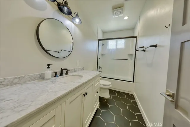 a bathroom with a granite countertop sink a toilet and a mirror