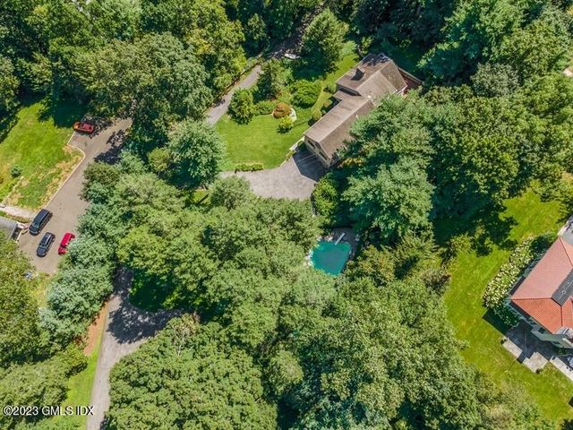an aerial view of residential house with outdoor space and trees all around